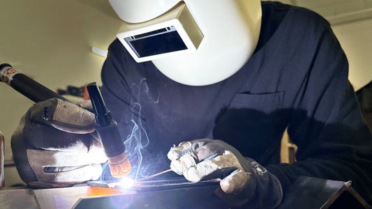A welding student practicing TIG on metal coupons.