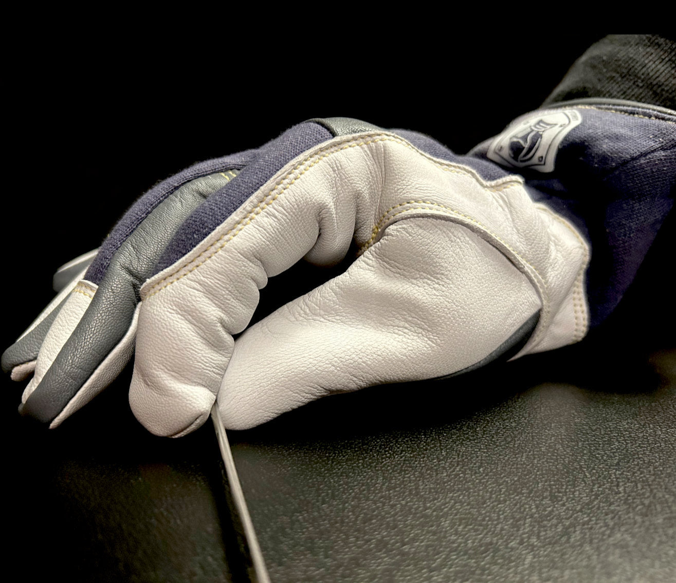 Flexible TIG glove picking up a small filler rod